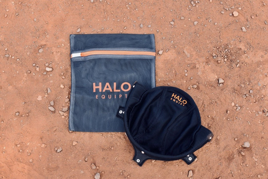 Black HALO Wash Bag on red dirt beside a black HALO Lid Liner lying open.