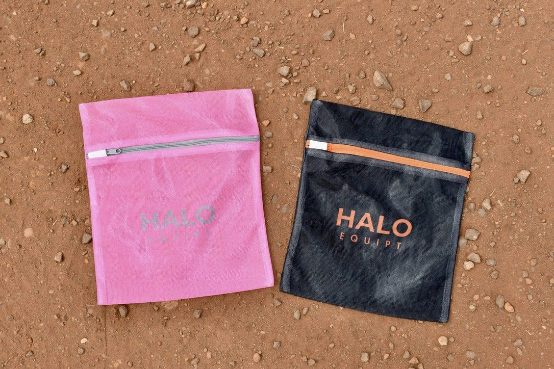 Black and pink HALO Wash Bags side by side on red dirt on a worksite.