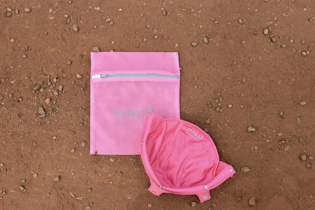 Pink HALO Wash Bag on red dirt beside a pink HALO Lid Liner lying open.