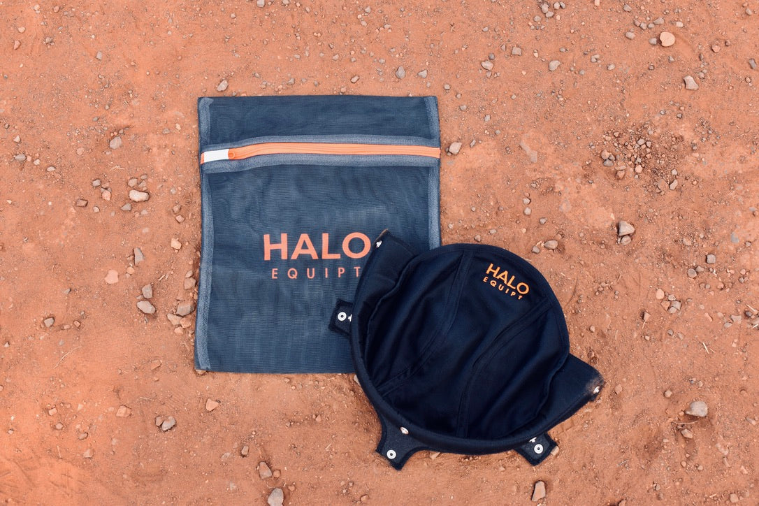 Black HALO Lid Liner lying open on red dirt beside the black HALO Wash Bag.
