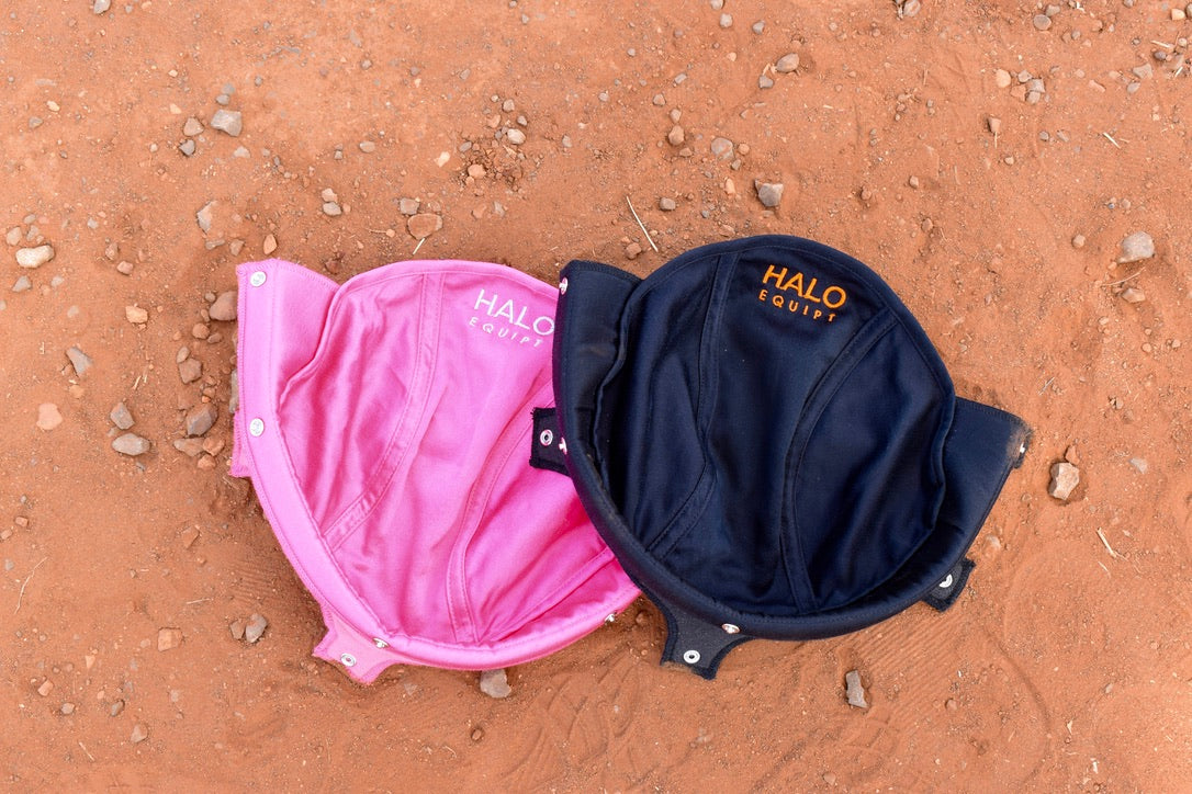 A black and a pink HALO Lid Liner side by side on red dirt.
