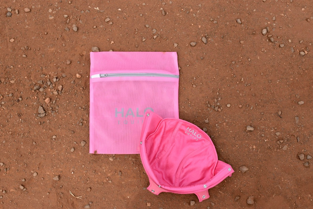 Pink HALO Lid Liner lying open on red dirt beside the pink HALO Wash Bag.